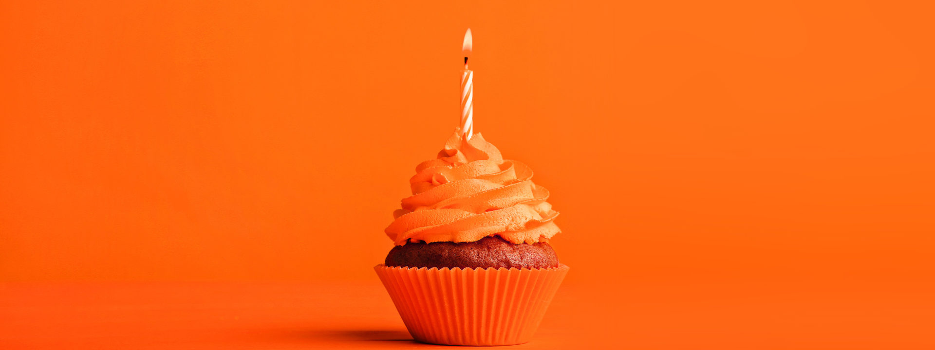 cupcake with orange icing and single candle