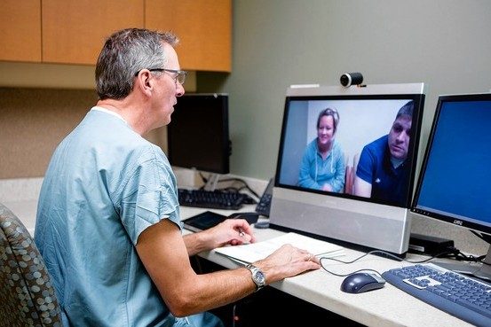 a doctor sitting at a desk doing teleconferencing with a patient to illustrate how to talk to your doctor about medical cannabis.